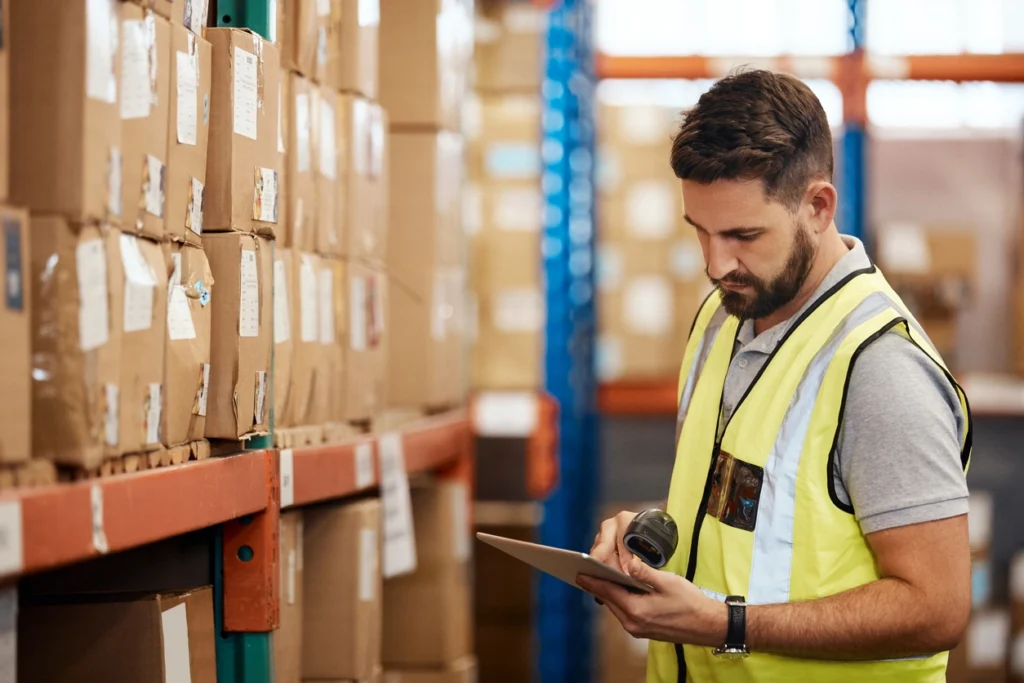 Man in warehouse using RFID scanner to scan inventory in boxes on racks
